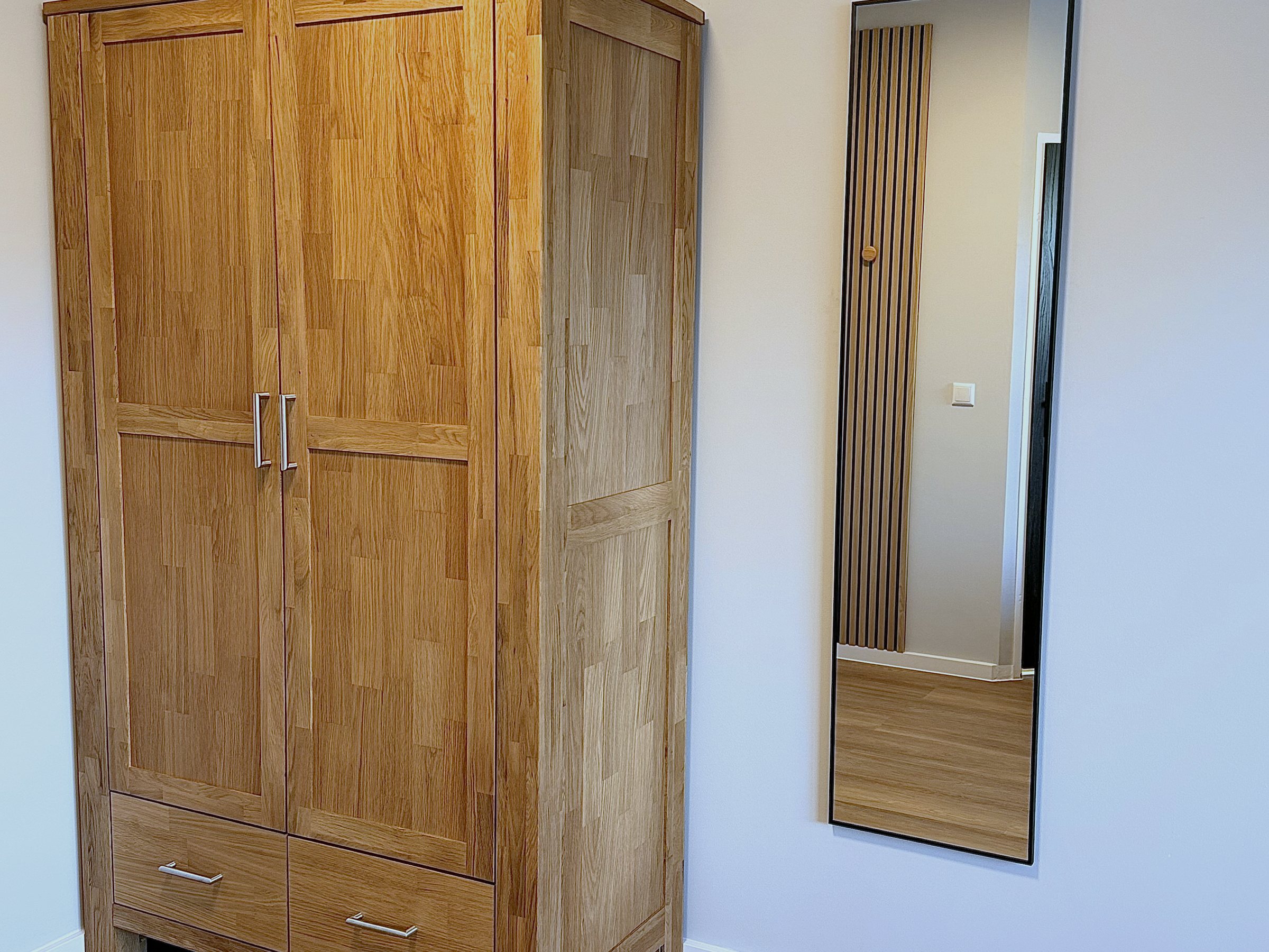 Kleiderschrank aus Massivholz mit Standspiegel im Zimmer